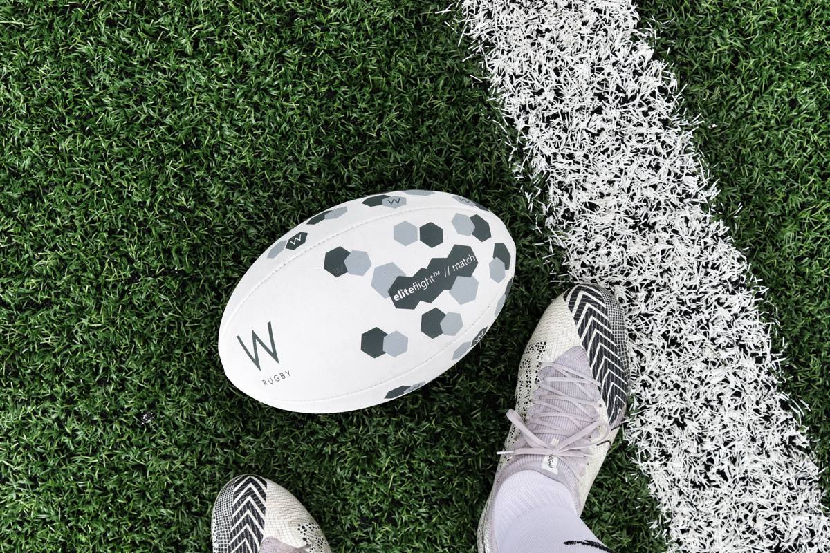 A rugby ball resting on the try line next to a pair of boots